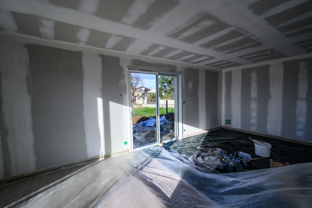 A basement or ground floor room that is being remodeled. Walls are bare, equipment is around, but progress is ready to be made